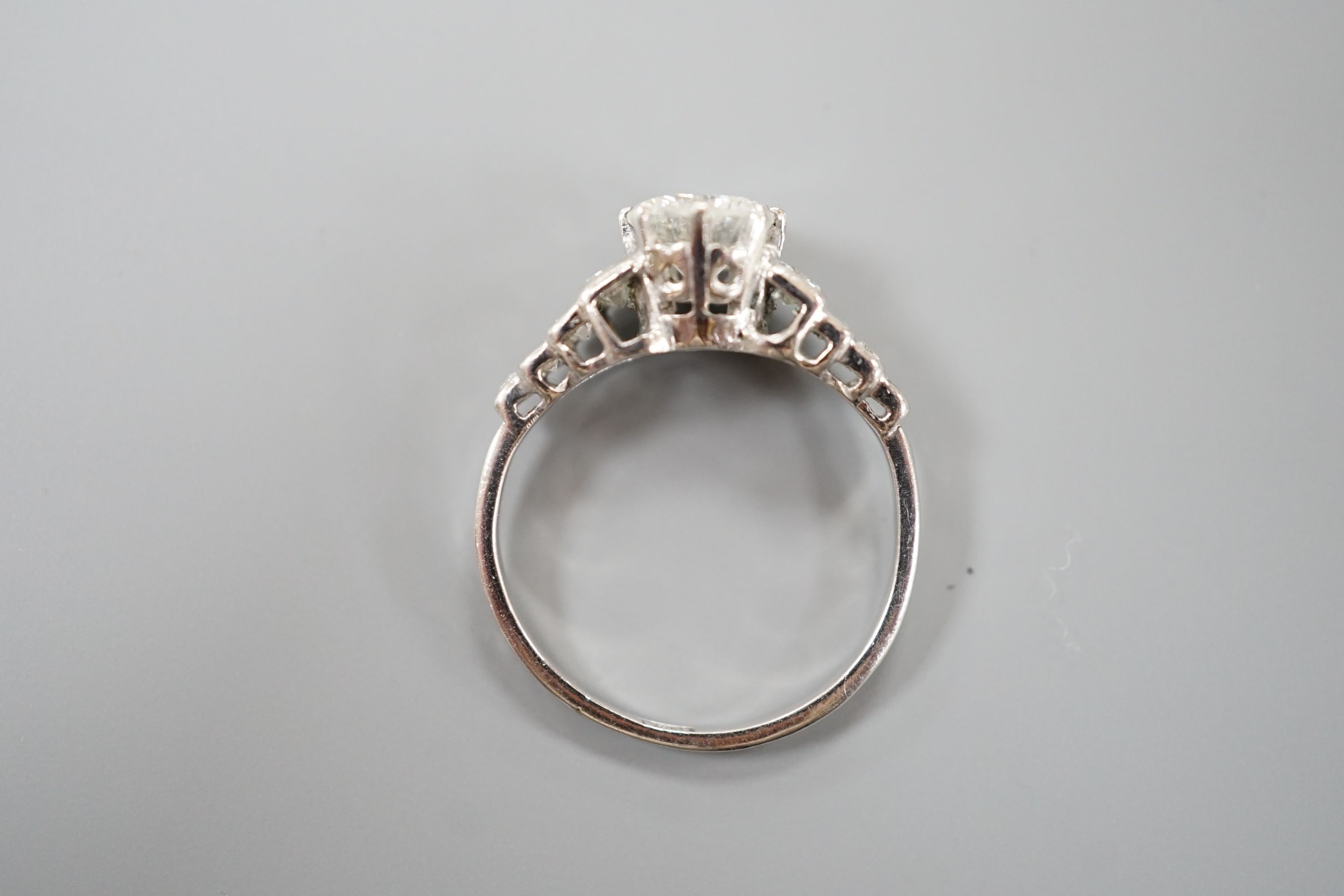 A white metal (stamped Plat) and single stone diamond ring, with graduated eight stone baguette cut diamond set shoulders, size K/L, gross weight 3.5 grams